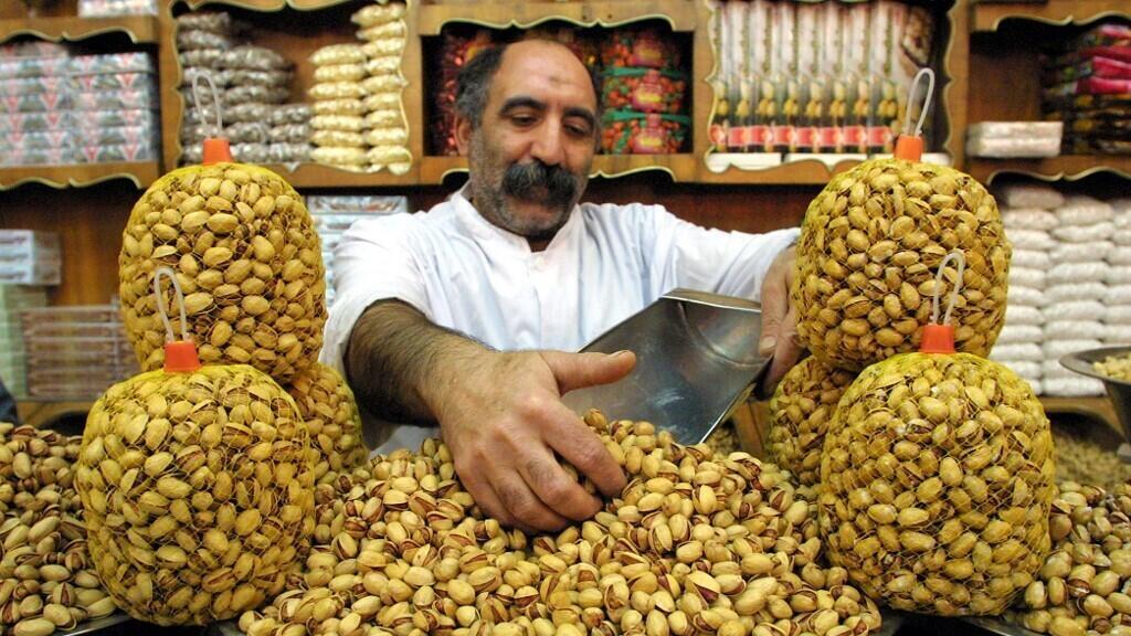 Montón de pistachos con cáscara sobre superficie de madera