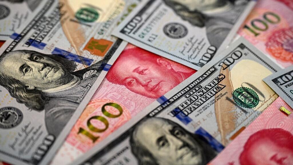 Billetes de yuan chino y dólares estadounidenses sobre una superficie