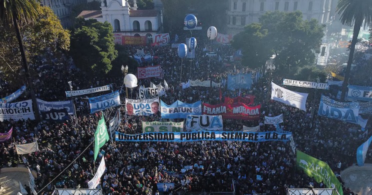 Multitud de estudiantes y docentes marchando con banderas universitarias