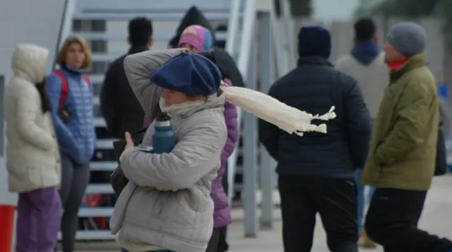 Personas abrigadas caminan bajo la lluvia en una calle de Buenos Aires