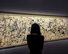 Cuadro abstracto de Jackson Pollock con salpicaduras de pintura negra, blanca y roja sobre fondo beige