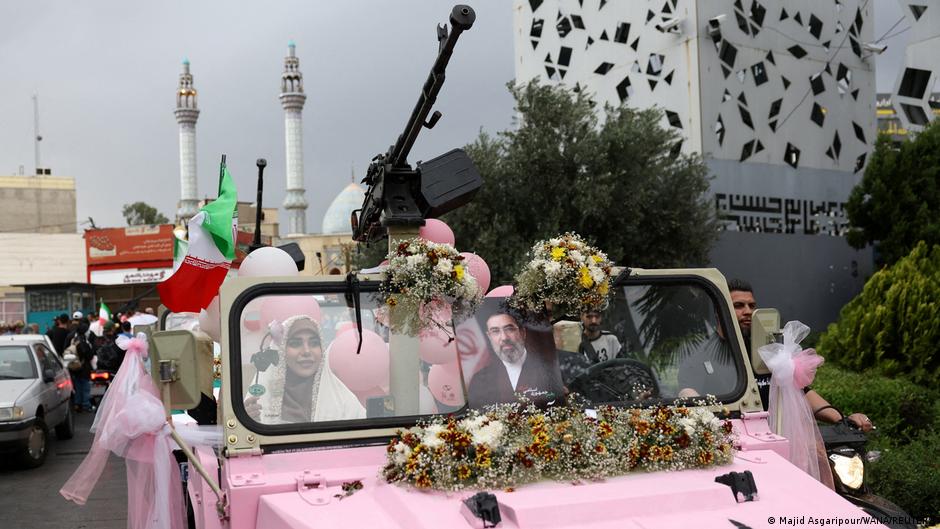 Parejas vestidas de blanco en una ceremonia nupcial masiva en Teherán con banderas iraníes