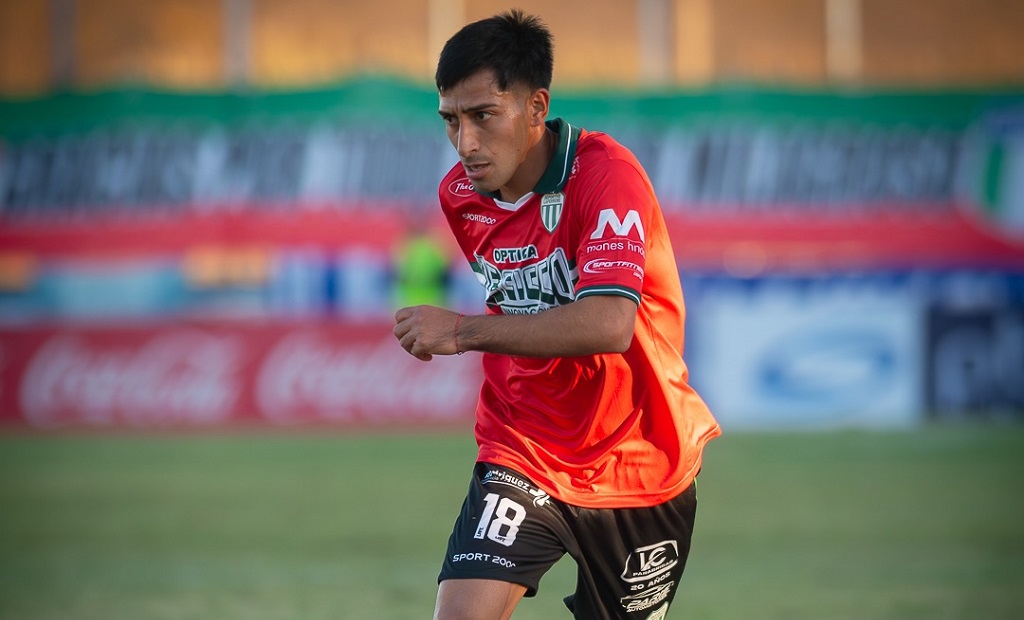 Jugador de fútbol con camiseta verde y blanca en una cancha