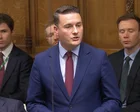 Wes Streeting hablando en un atril con micrófonos