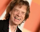Mick Jagger en una alfombra roja con traje oscuro y gafas de sol