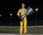 Kyle Busch con el uniforme de Nascar junto a su auto de carreras