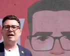 Andy Burnham sonriendo con un teléfono en la mano