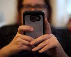 Mujer revisando su teléfono con expresión preocupada