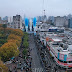 Desfile cívico-militar en avenida de San Miguel con público y banderas argentinas