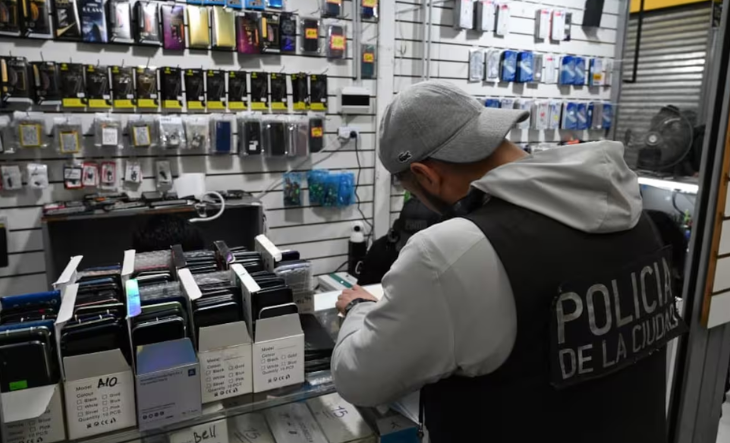 Efectivos policiales revisan teléfonos celulares secuestrados sobre una mesa