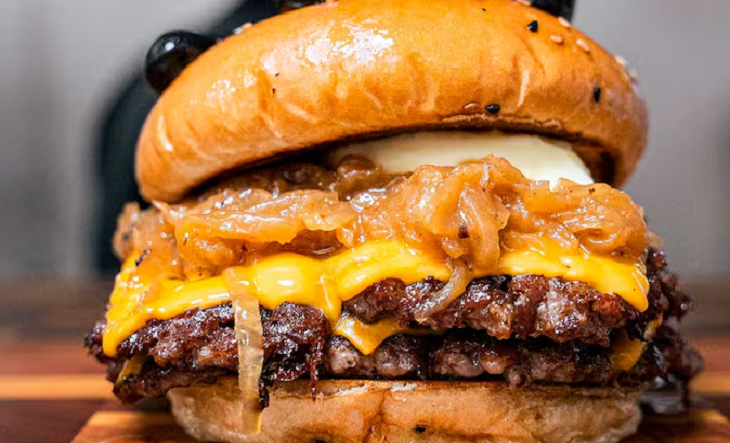 Hamburguesa con queso, vegetales y papas fritas sobre una mesa