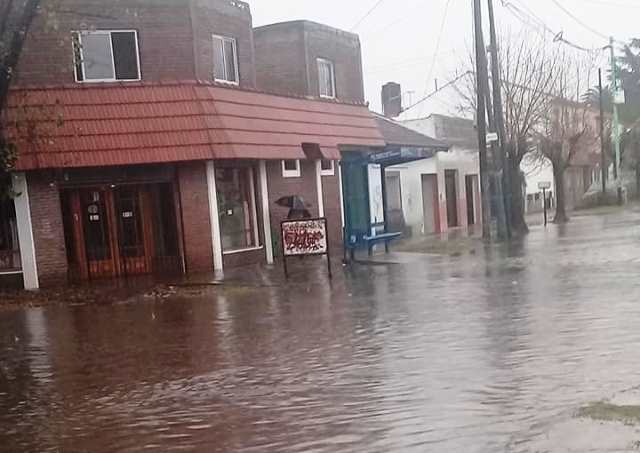 Calle mojada con edificios de fondo y cielo nublado