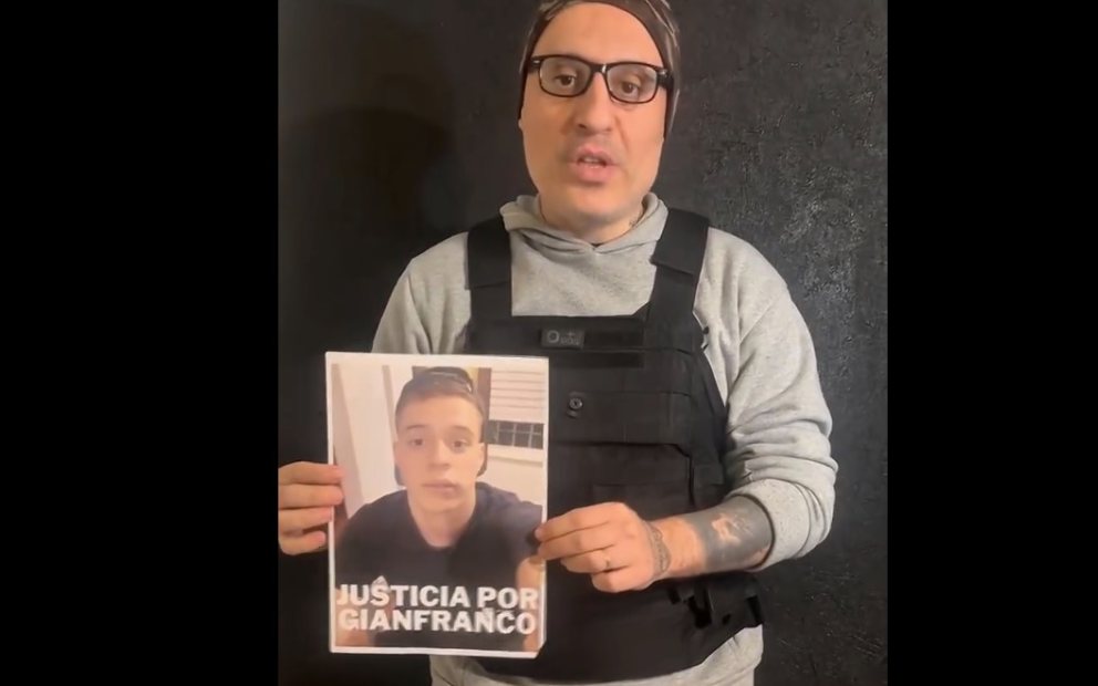 Hombre con chaleco antibalas sosteniendo un teléfono frente a su rostro