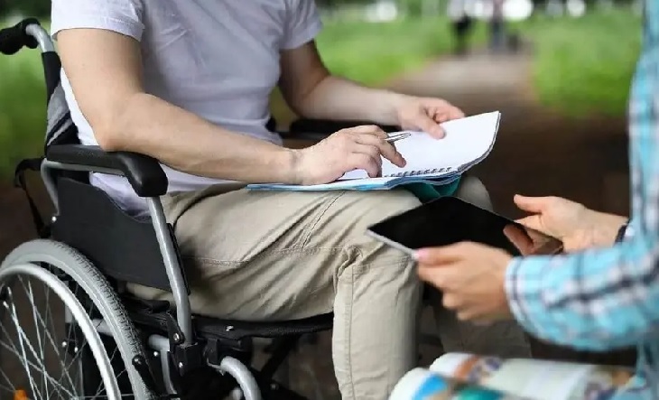 Persona con discapacidad en silla de ruedas junto a un profesional de la salud
