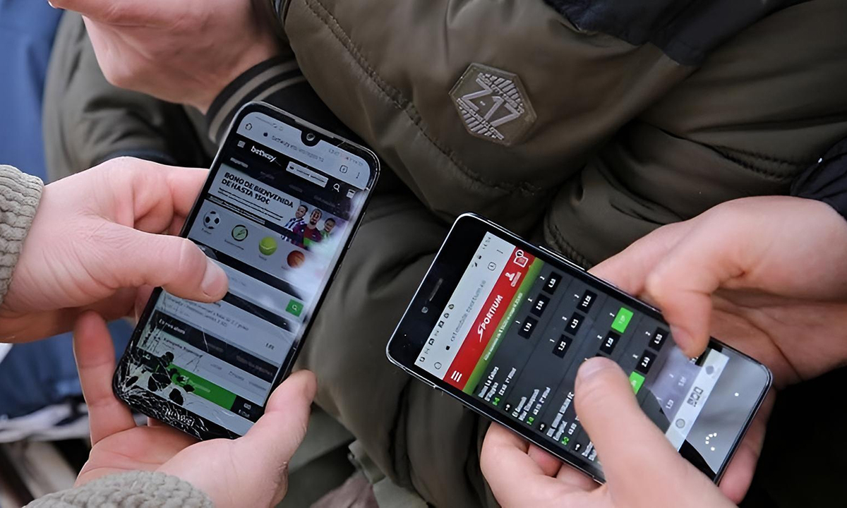 Adolescente mirando un celular con pantalla de apuestas deportivas