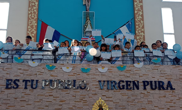 Alumnos de cuarto grado con banderas argentinas en una ceremonia escolar