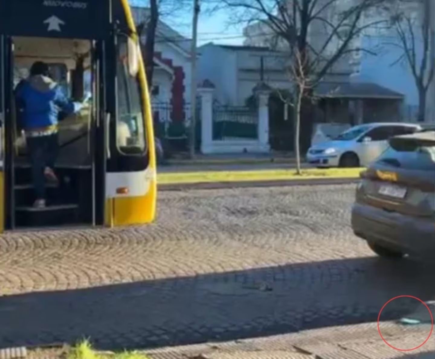 Colectivo detenido en la calle con la puerta abierta mientras dos hombres forcejean