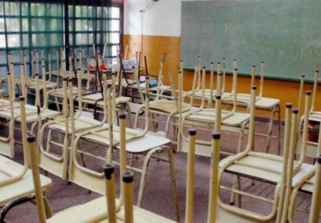 Docentes con carteles de reclamo frente a una escuela