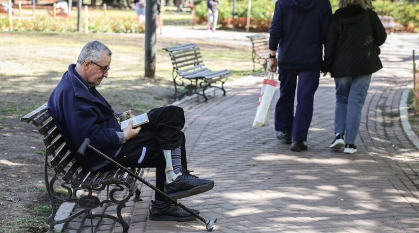 Persona mayor con documento y billetes sobre mesa