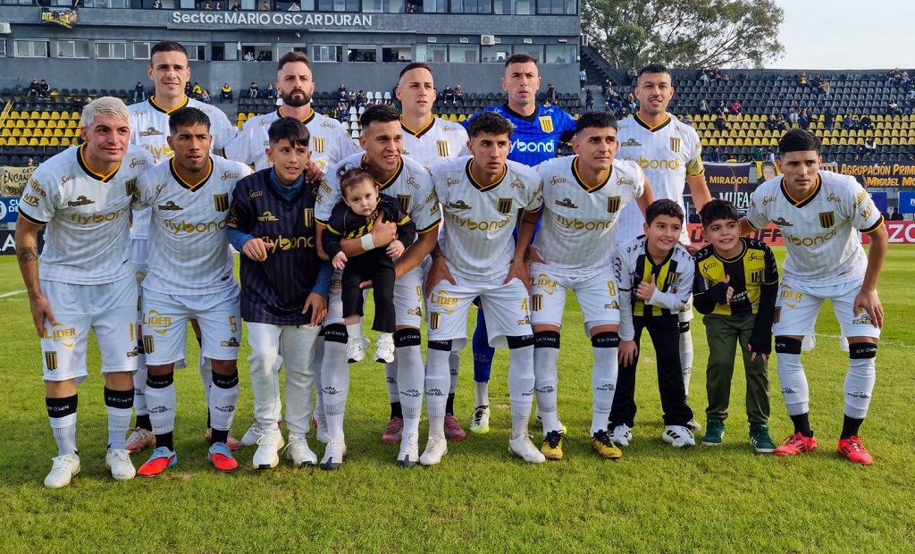 Jugadores de fútbol en una cancha con público de fondo