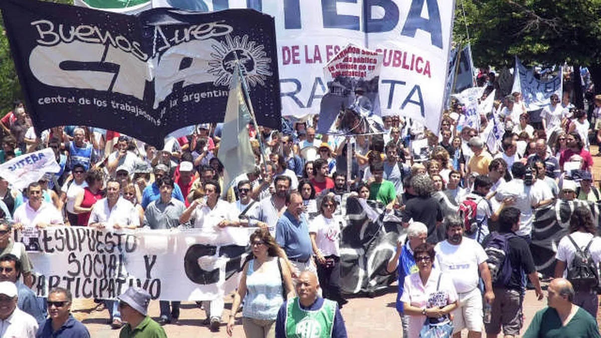 Docentes en una asamblea con carteles de reclamo salarial