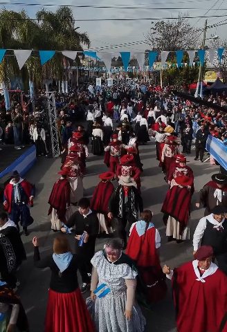 Multitud de vecinos con banderas argentinas en un desfile patrio en La Matanza