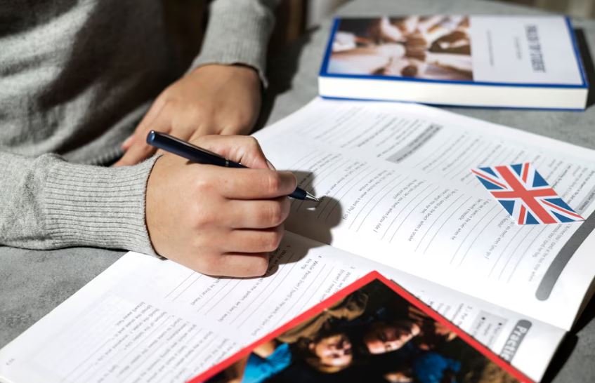 Persona estudiando inglés con auriculares y computadora