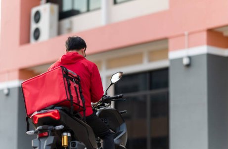 Repartidor en bicicleta con mochila de delivery en la calle