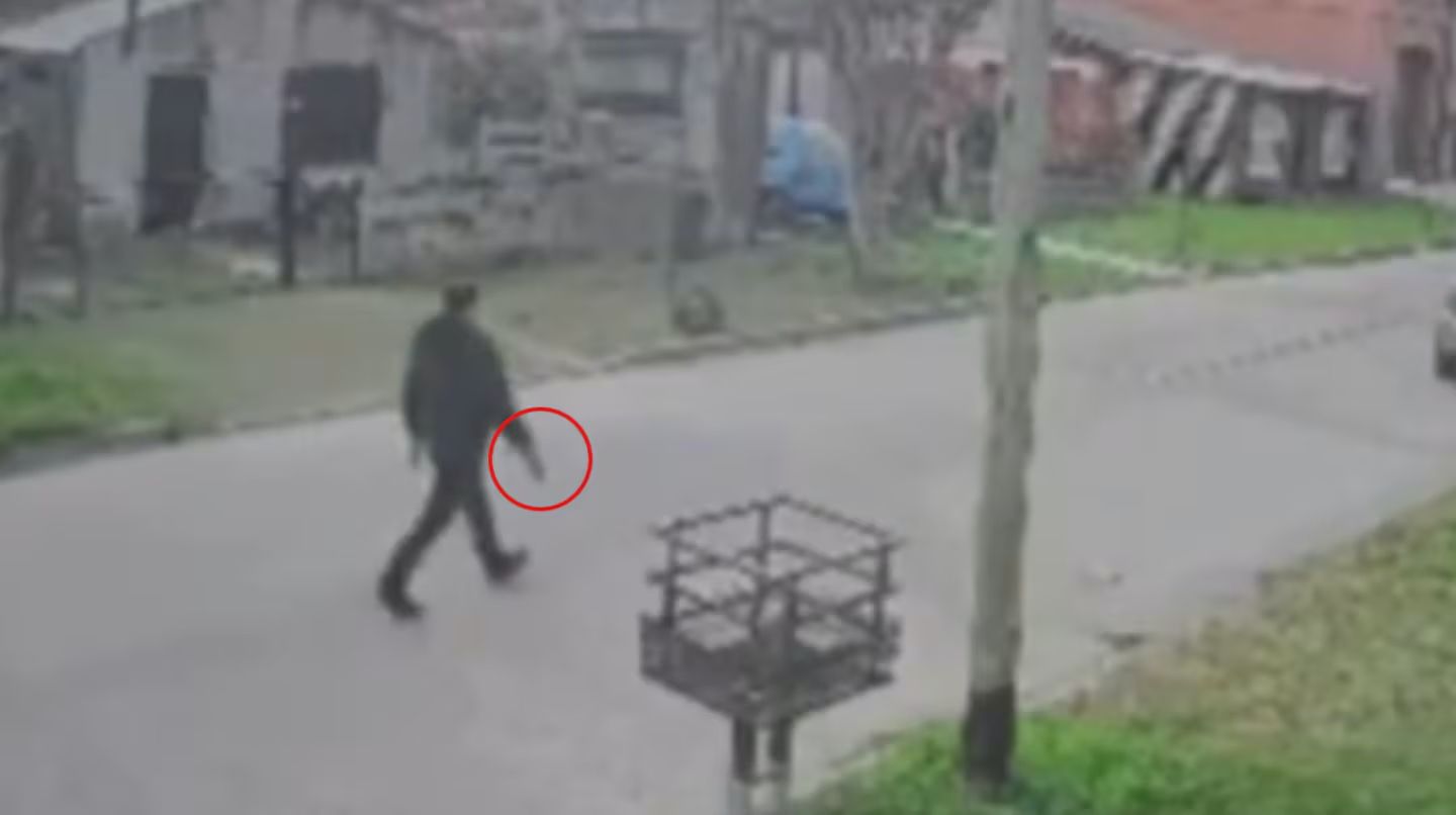 Policía en la puerta de una vivienda con fachada con impactos de bala