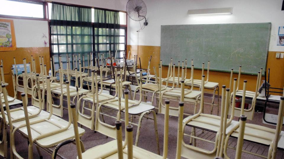 Docentes con carteles de protesta frente a una escuela
