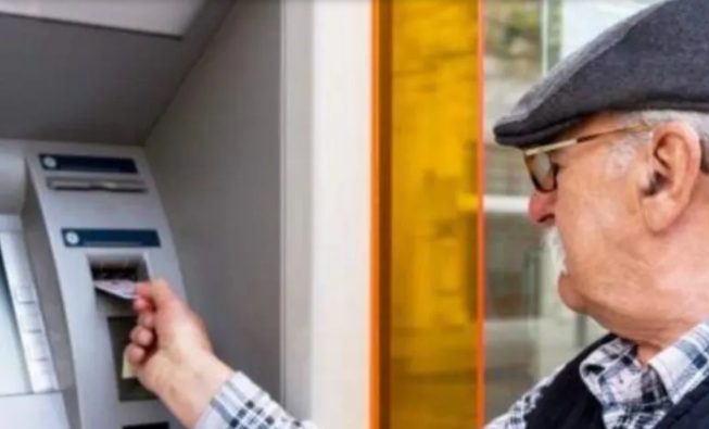 Persona mayor con documento en la mano frente a una oficina de ANSES