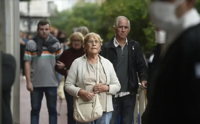 Personas mayores caminando por una calle con bolsas de compras