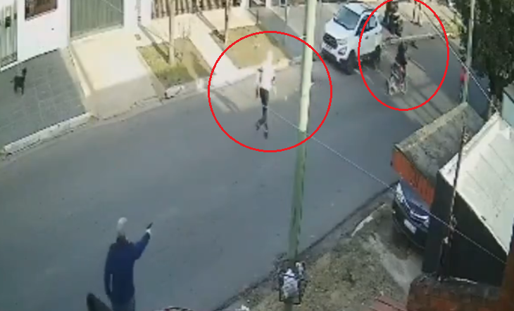 Cámara de seguridad muestra a un hombre apuntando con arma a motochorros en la calle