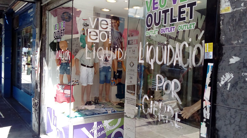 Vidrieras con carteles de liquidación y locales vacíos en una calle de San Justo