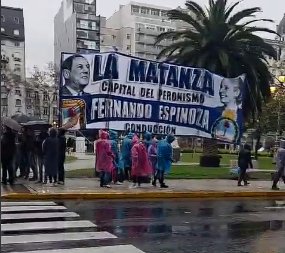 Columna de manifestantes con banderas marchando bajo la lluvia frente al Congreso