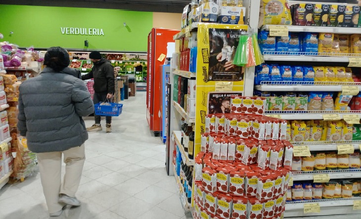 Personas haciendo compras en un supermercado con precios en góndola