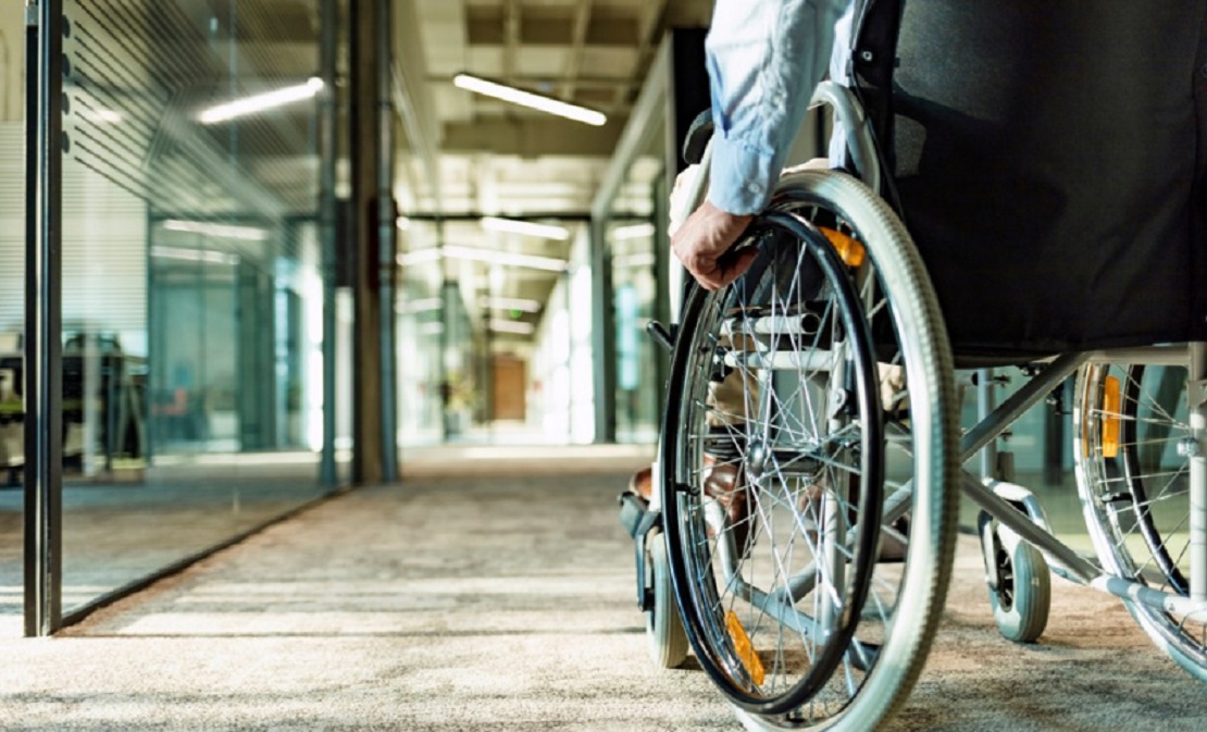 Persona en silla de ruedas junto a un profesional de la salud en un centro de día