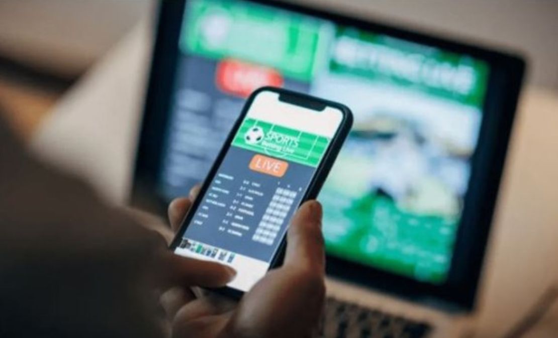 Persona usando un teléfono móvil con una aplicación de apuestas deportivas