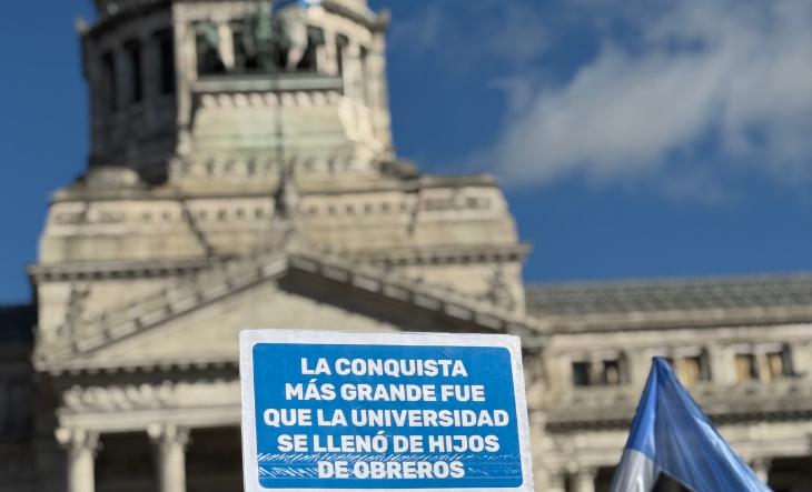 Docentes universitarios en una asamblea frente a una facultad