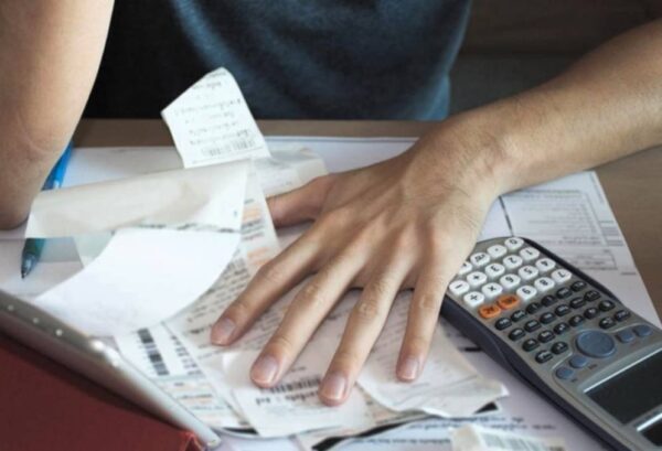 Persona revisando facturas y calculadora en una mesa