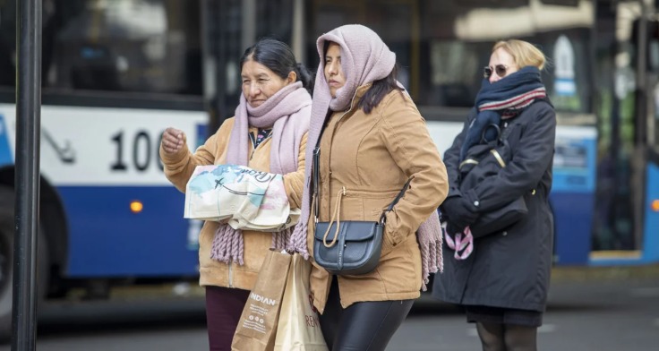 Personas abrigadas caminando por una calle de Buenos Aires en un día frío