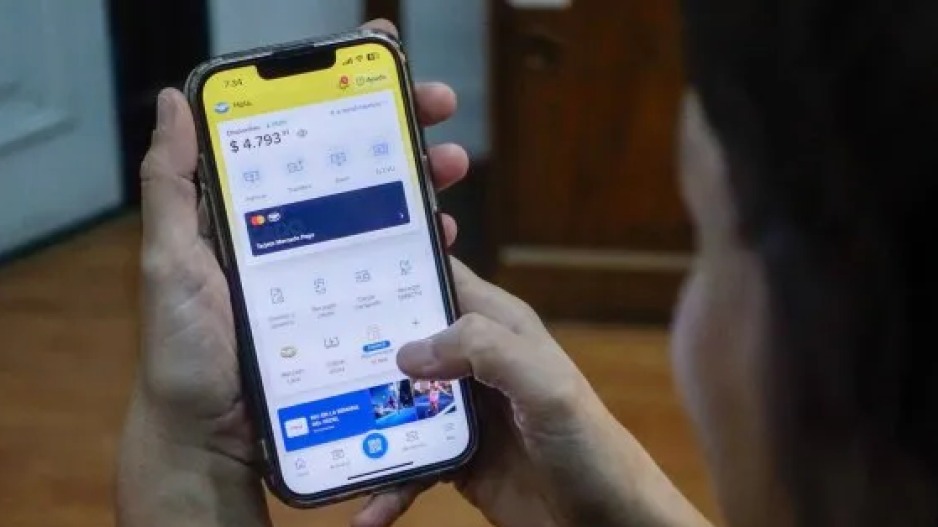 Personas consultando sus teléfonos móviles en una fila de un banco