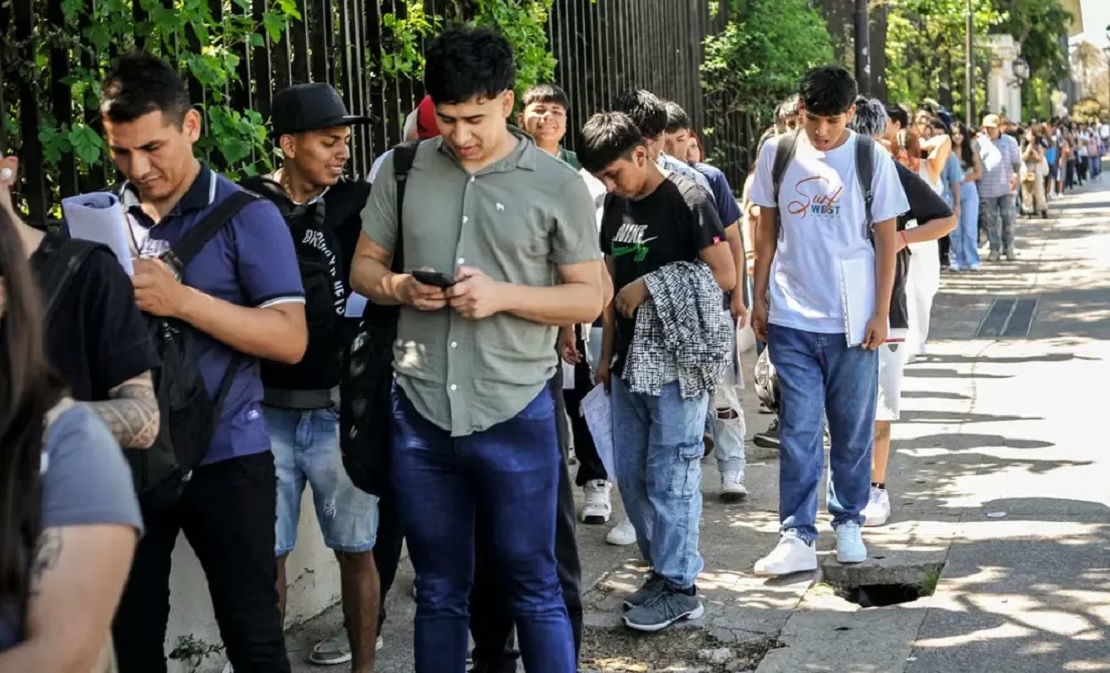 Personas esperando en una oficina de empleo con formularios en mano
