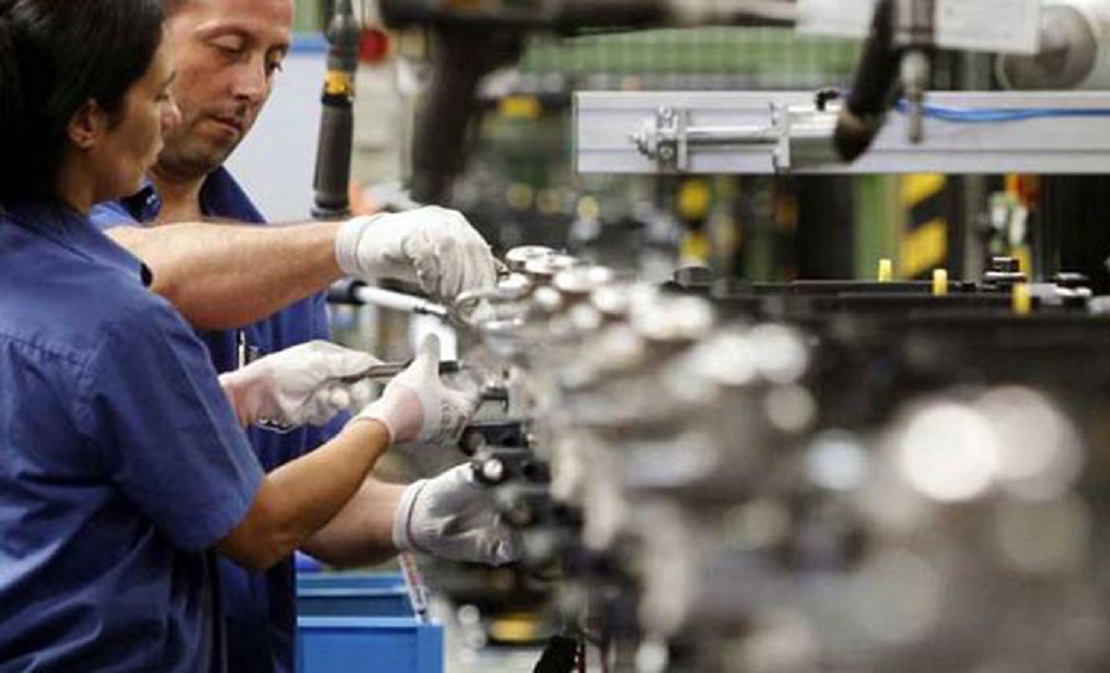 Fábrica con máquinas detenidas y operarios en un galpón industrial